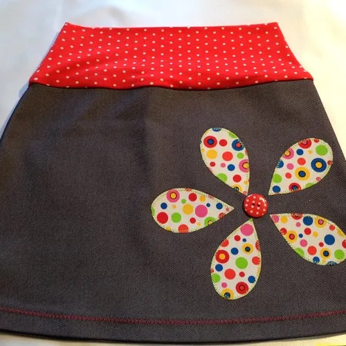 Girls' light stretch denim skirt with wide red and white polka dot belt and appliqués.